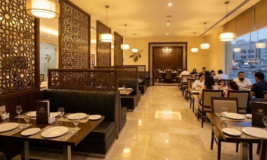 Modern luxury interior of Zaitoon Restaurant in Doha Qatar, featuring comfortable plush family booths, warm golden lighting, elegant Arabic geometric partition screens, and clean VIP dining tables.