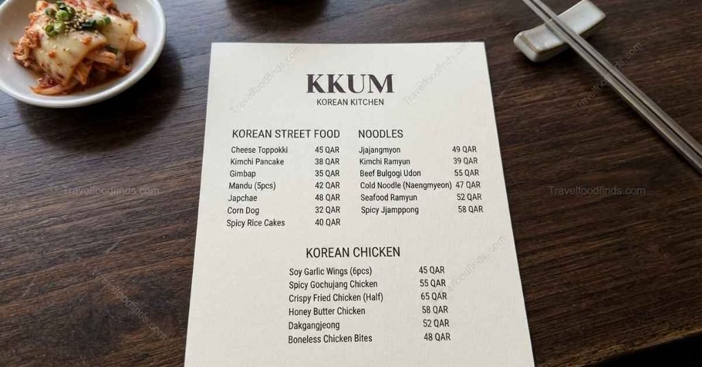 A printed Kkum Korean restaurant menu showing prices in QAR for street food and noodles.